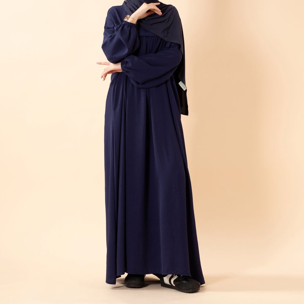 Overhead flat lay of crepe Hajj abaya showing all pockets