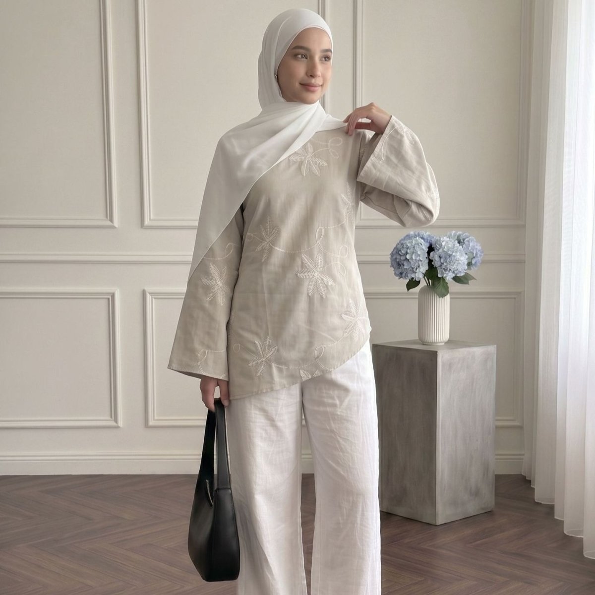 Movement shot showing wide flared sleeve drape on embroidered asymmetric top