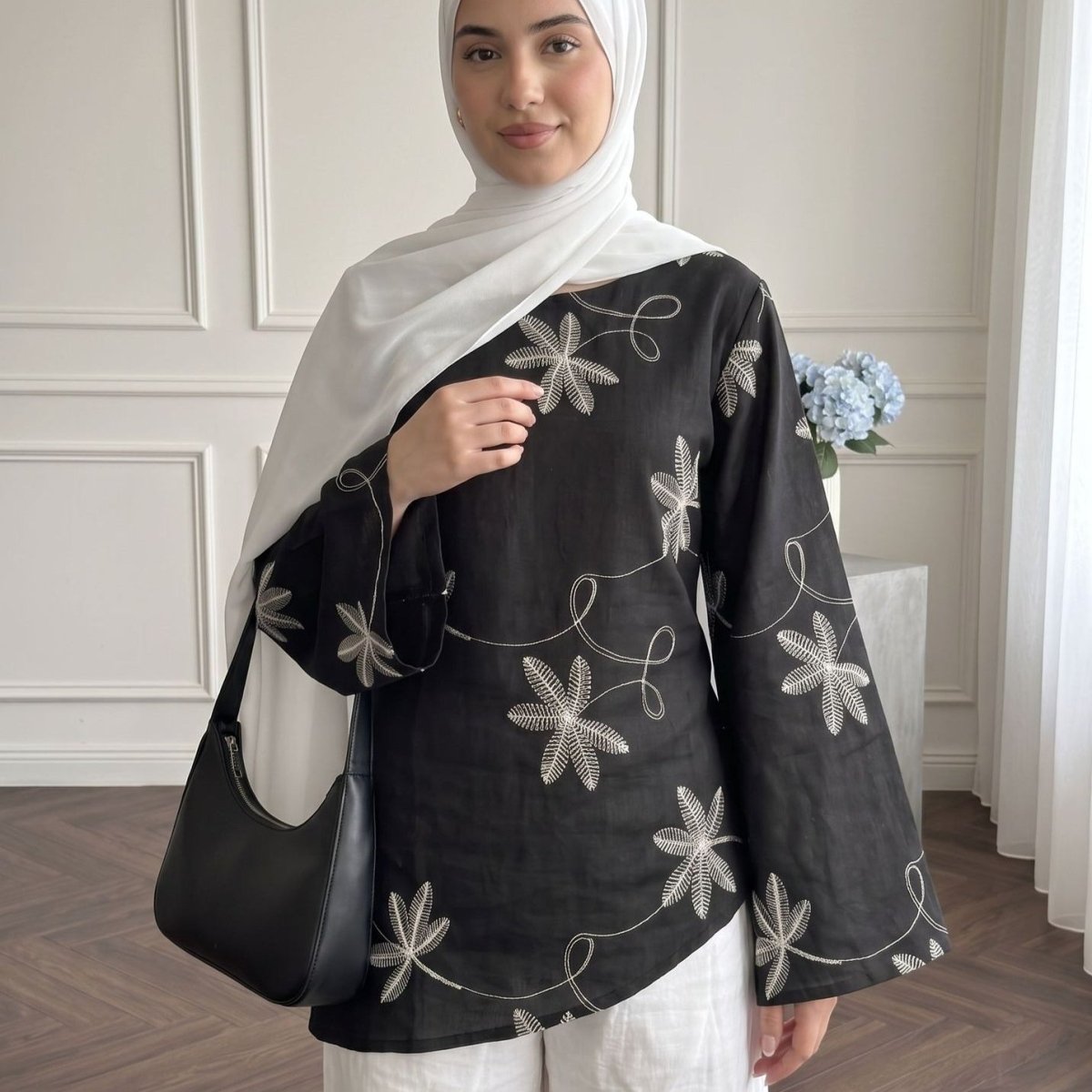 Front view of white botanical embroidery detail on structured modest top